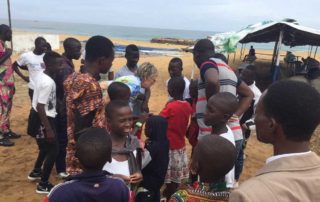 Margret Kopp umringt von Kindern und Jugendlichen am Strand von Lomé
